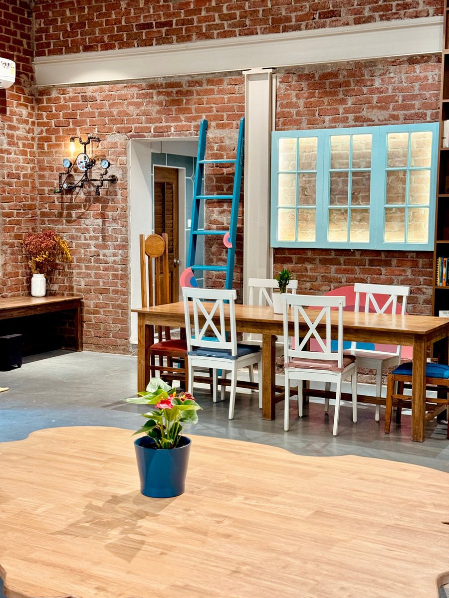 Brick-walled corner of the Gather studio with a blue ladder and colourful chairs