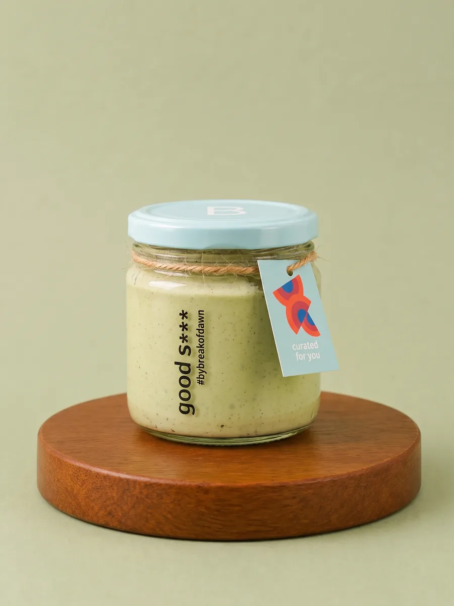 A jar of Break of Dawn high protein pesto pasta sauce on a wooden board