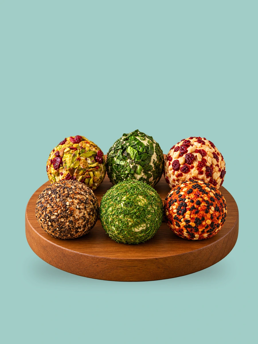 A walnut board of six Break of Dawn feta bombs: cranberry pistachio, basil, chilli garlic, peppercorn, dill and podi