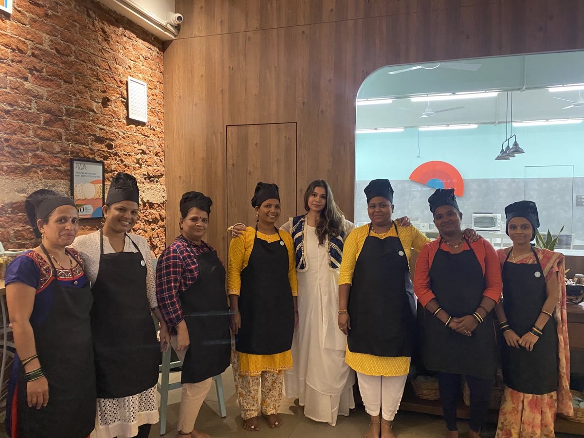 The all-women Break of Dawn team in the Govandi East kitchen, in aprons and chef caps, with Pardita